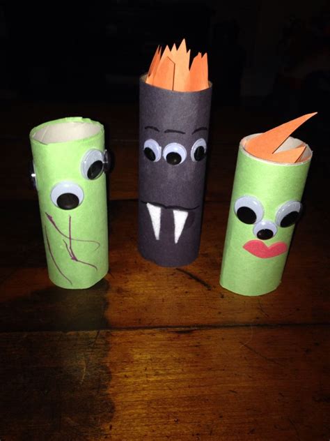 three toilet paper rolls with faces and mouths on them, sitting on a wooden table