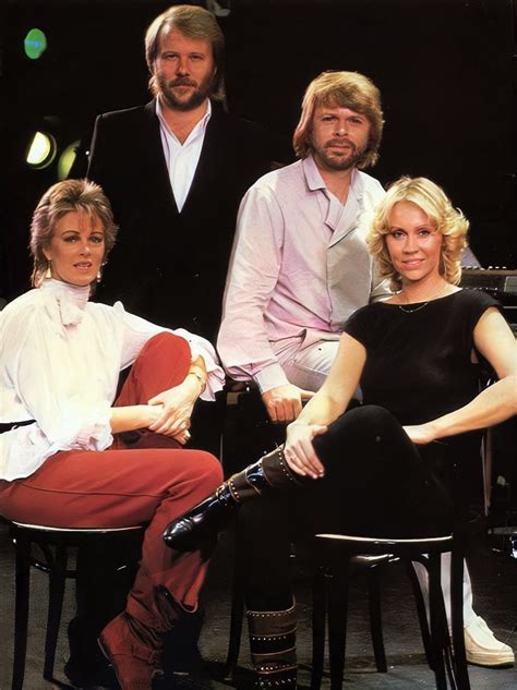 four people sitting on chairs in front of a piano and one person standing behind them