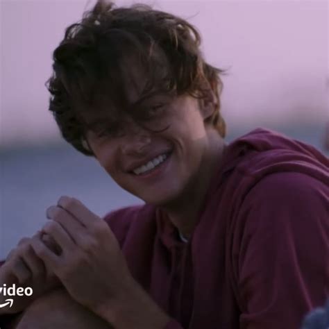 a smiling young man with his hands folded over his chest and looking at ...