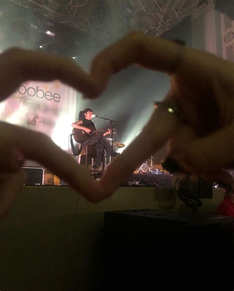 two hands making a heart shape at a concert