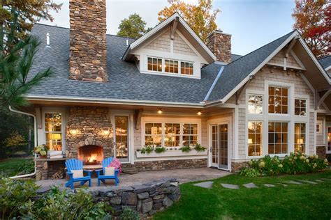 a house with two chairs and a fire place in front of the porch, surrounded by greenery