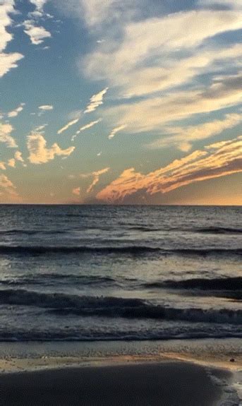 the sun is setting over the ocean with clouds in the sky and waves on ...