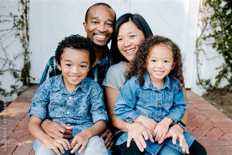 Portrait of happy mixed race family on porch Stock Photo | Adobe Stock