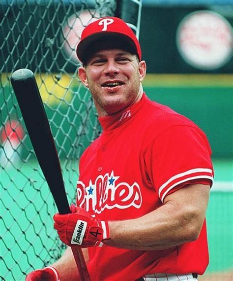 a man holding a baseball bat on top of a field in front of a fence