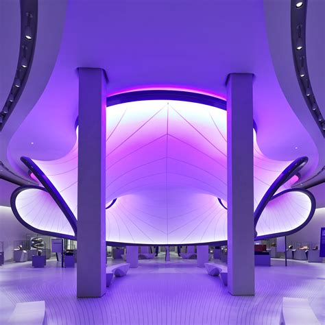 the interior of a modern building with purple lighting and white benches in front of it