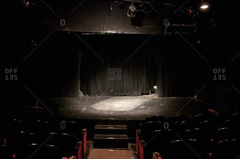 Empty stage lit by a spotlight in a small theater stock photo - OFFSET