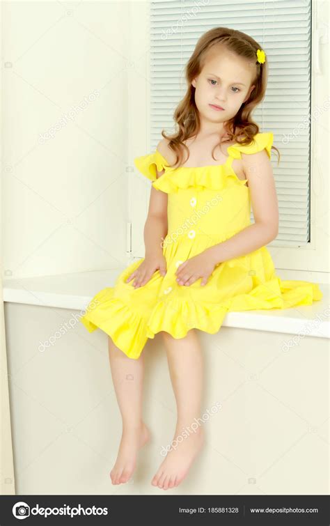 A little girl is sitting by the window with jalousie Stock Photo by ...