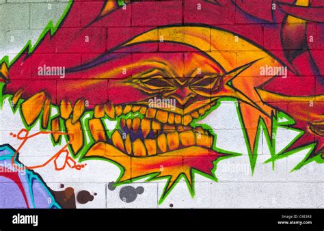 An evil face painted in a graffiti image on a white painted block wall ...