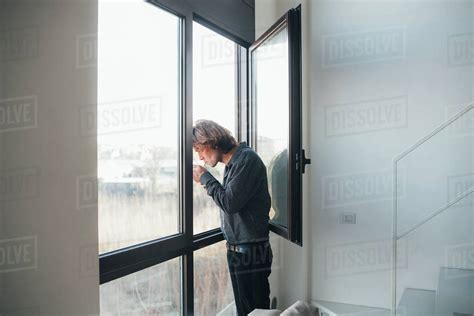 Businessman smoking out of window - Stock Photo - Dissolve