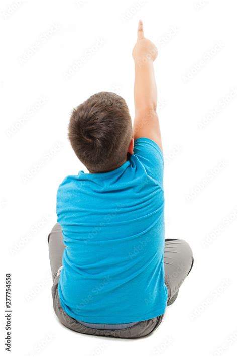 Back view of little boy sitting on floor, points at wall. Rear view ...