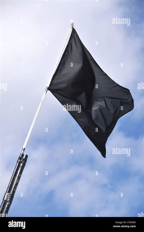 A blank black flag flying in the wind against a cloudy blue sky Stock Photo - Alamy