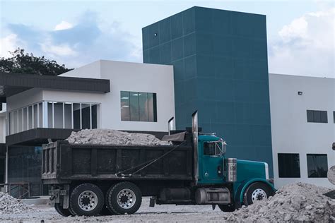 A Dump Truck Loaded with Sand Near Concrete Building · Free Stock Photo