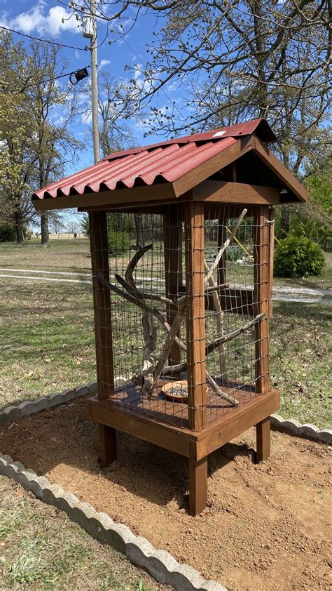 a bird cage in the middle of a park