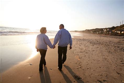 Elderly Couple Holding Hands And Walking On The Beach | Stocksy United