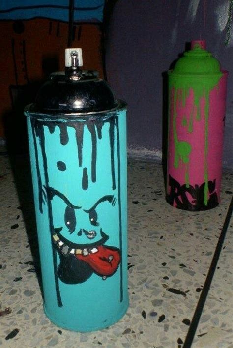 two spray paint cans sitting next to each other on the ground with graffiti all over them