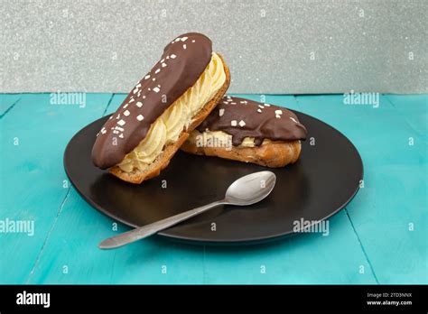 Two eclair cakes on a black ceramic plate, and blue wooden boards table Stock Photo - Alamy