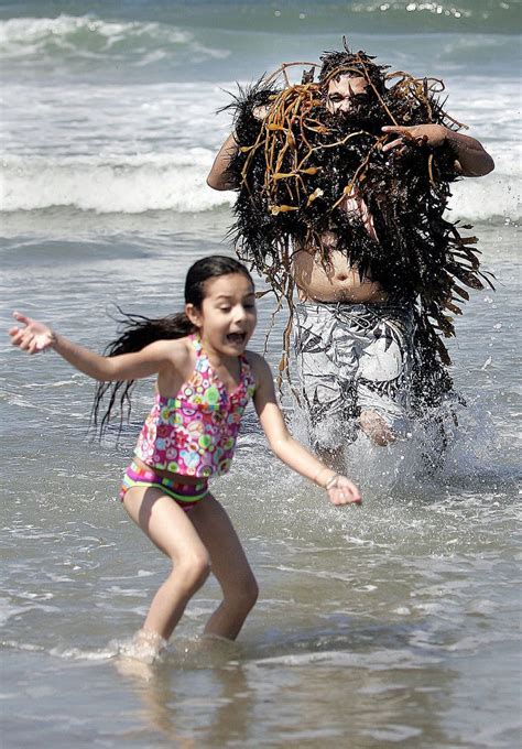 海で海草お化けに扮したお父さんと、それを見て逃げる娘（笑）