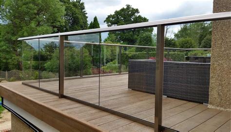 a wooden deck with glass railing and furniture