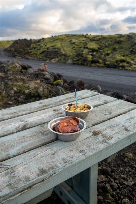 Metal Bowls with Lamb Steaks and Potatoes on Wooden Picnic Table. Stone Landscape, Iceland Stock ...