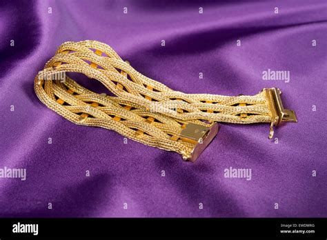 Gold bracelet isolated on purple satin background Stock Photo - Alamy