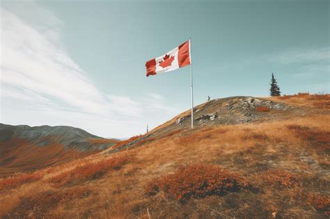 Premium Photo | A canadian flag on a hill with the mountains in the background.