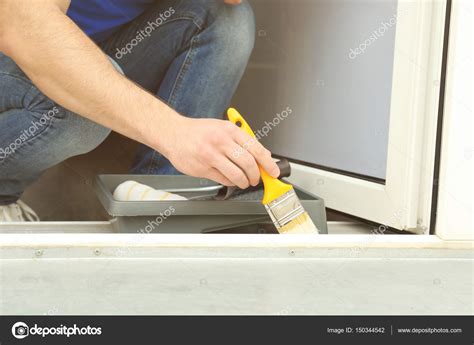 Young man painting window — Stock Photo © belchonock #150344542