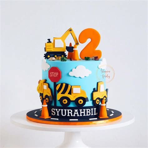 a blue and yellow cake with construction vehicles on it's top is the ...