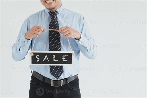 Crop shot of smiling sales man wearing blue shirt and tie posing with carrying sale sign board ...