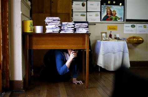 A teacher takes cover under her desk inside a school during an ...