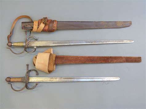 A pair of replica English Civil War swords with leather scabbards and belts, blade lengths 77cm a