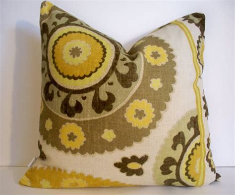 a yellow and brown decorative pillow on a white surface with an orange flowered design