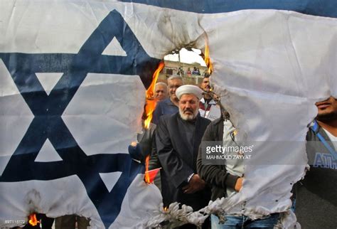 Protesters burn an Israeli flag during a demonstration, organized by Hezbollah, in the streets ...