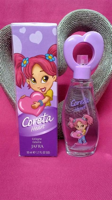 a bottle of perfume next to a box on a pink surface with a heart - shaped object in the background