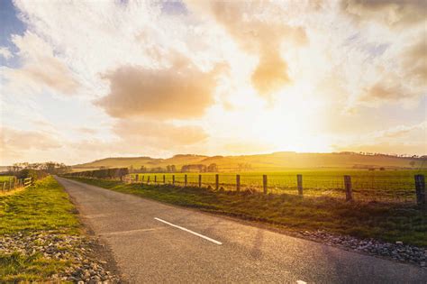 Empty country road in rural landscape at sunset stock photo