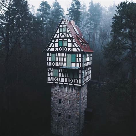 an old building with a red roof in the middle of some trees on a foggy day