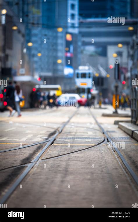 Streetcar tracks toward blurred urban traffic background with tram, car, unrecognizable people ...