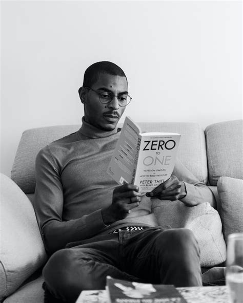 Young Man Sitting on the Sofa and Reading a Book · Free Stock Photo