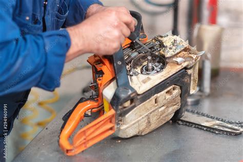 Mechanic repairing a chainsaw. Man repairing a chainsaw in workbench . Stock Photo | Adobe Stock