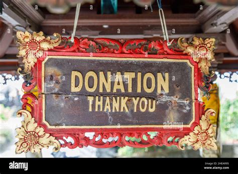 Wooden carved sign "DONATION Thank you" with golden decoration at Hindu ...