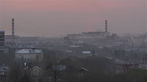 Night falls in an industrial city. Timelapse sunset and evening. Smoke, air pollution from ...