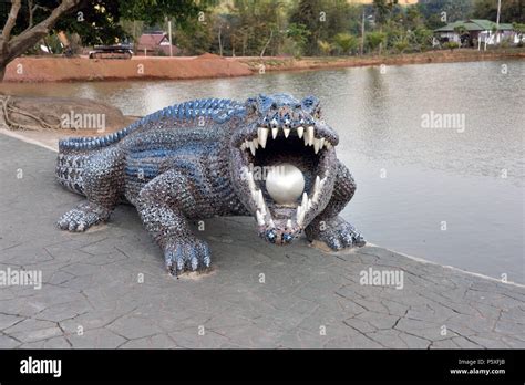 The blue and silver crocodile holding a silver ball in it's mouth in ...