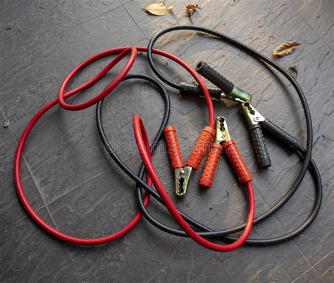 Car Battery Charging Cables In Red And Black Colors On Dark Grey Floor. Stock Photo - Image of ...