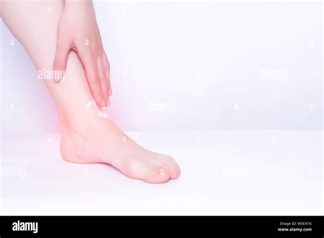 Girl smears medical ointment ankle on a white background, treatment of synovitis and bursitis ...