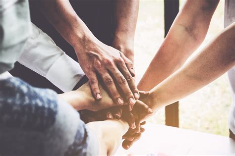 Group of business people putting their hands working together on wooden background in office ...