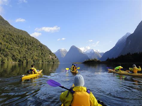 several people in yellow kayaks paddling on the water with mountains in the background