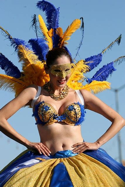 a woman in a blue and yellow costume with feathers on her head is posing for the camera