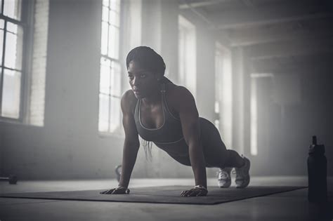 Black woman doing push-ups in dark gym. Photo by Gable Denims | Black athletes, Push up, Circle ...