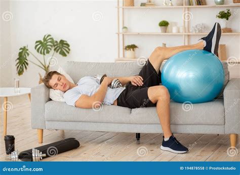 Laziness and Workout. Tired Guy Sleeping on Couch with Dumbbell and Fitness Ball Stock Photo ...