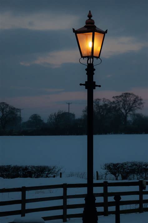 A traditional Victorian lamp post glowing on a winters evening ...