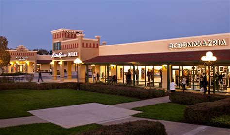 people are walking around in front of a shopping center at dusk, with ...